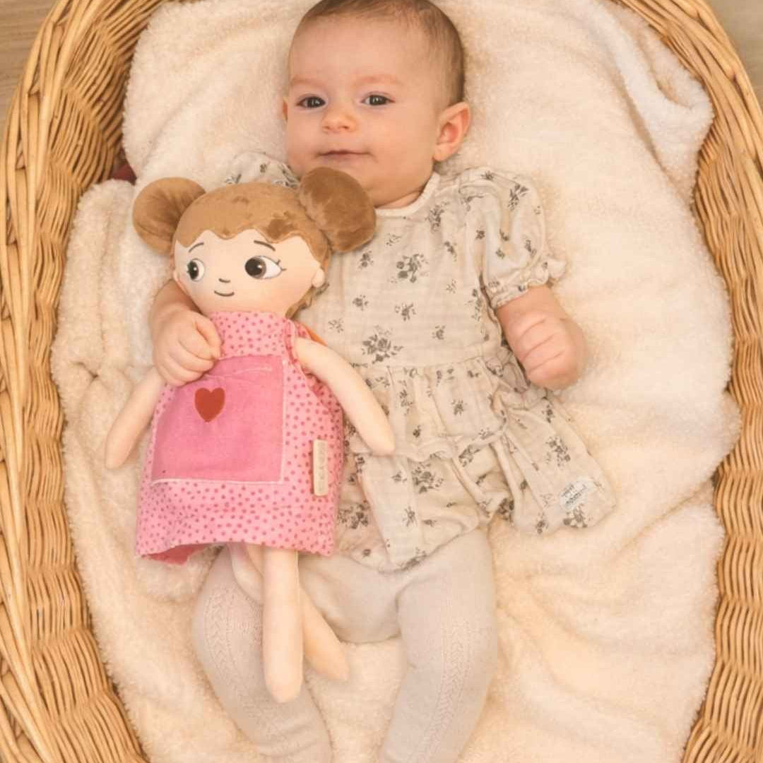 En bebis som håller i en mjuk watoto arts docka som den fått i dopgåva