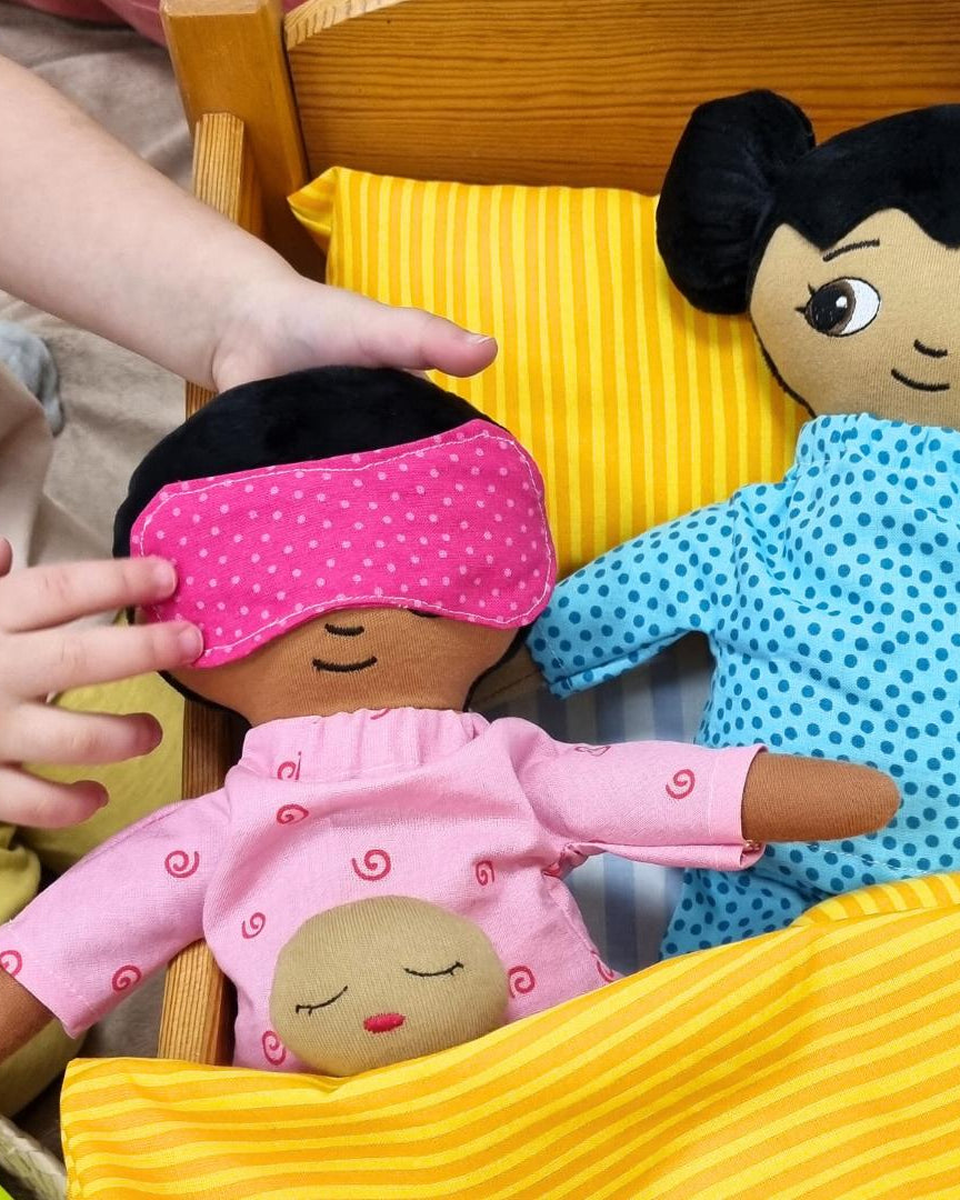 Två dockor som bär pyjamas och sover i en docksäng