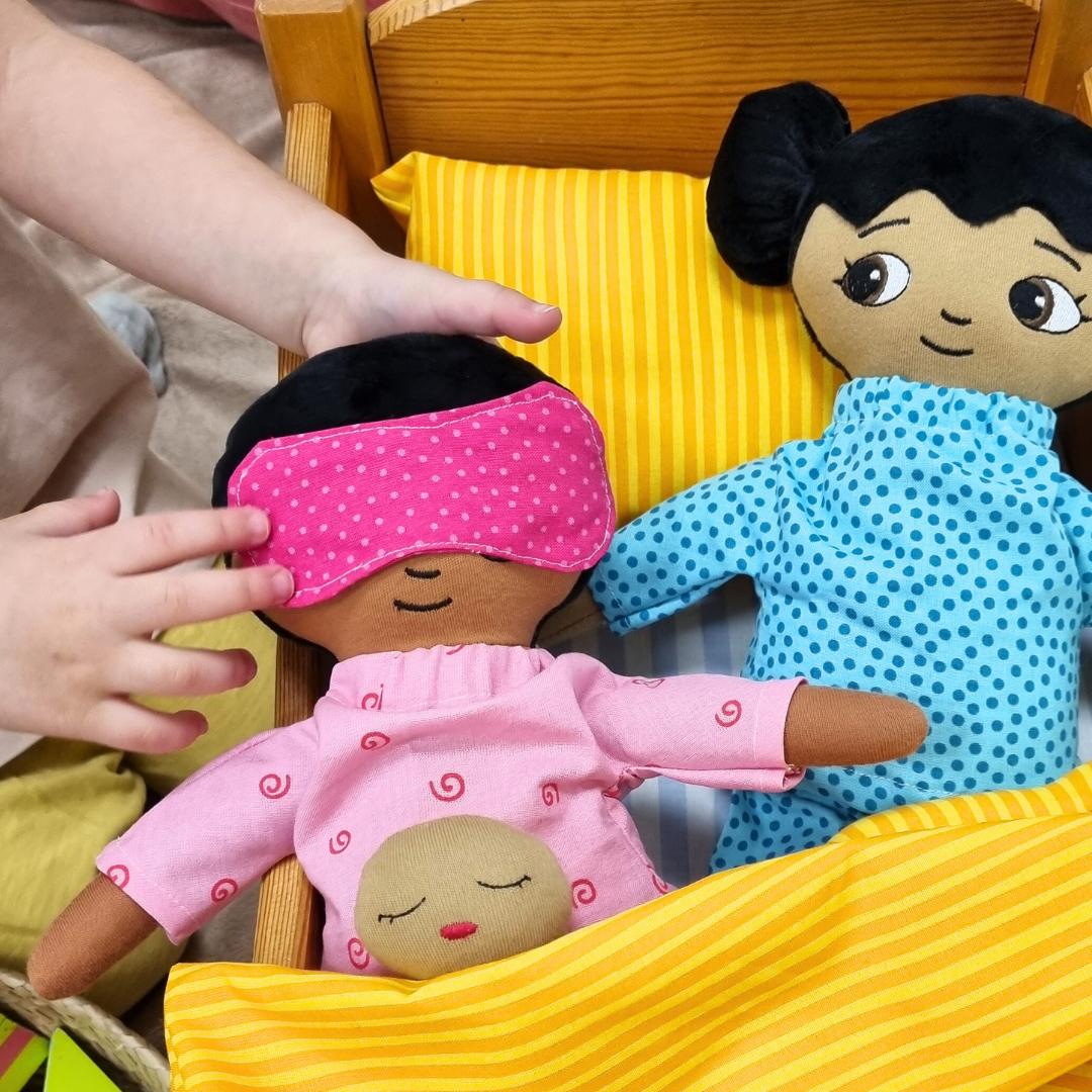 Två dockor som bär pyjamas och sover i en docksäng