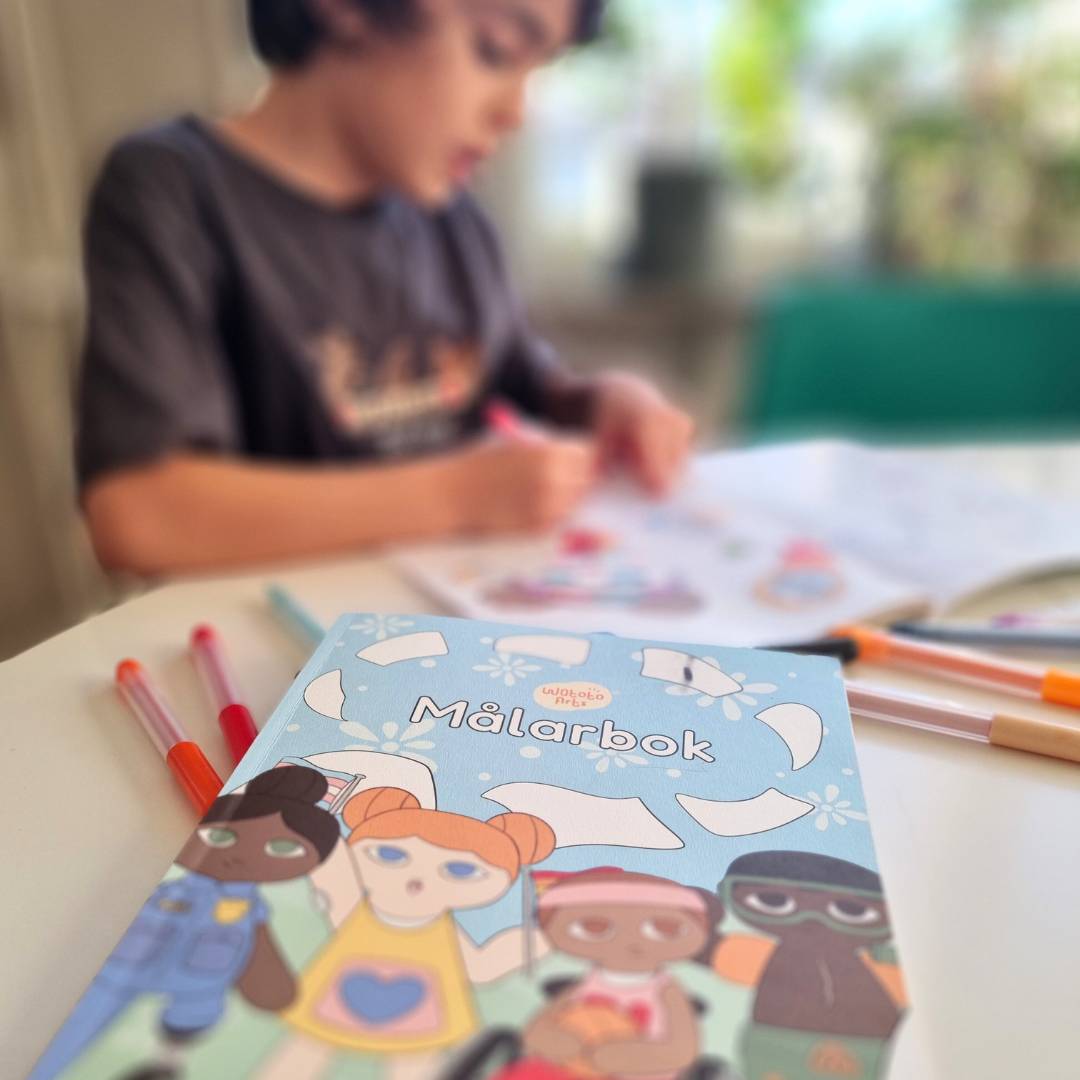 En pojke som målar i Watoto Arts målarbok med färgkritor