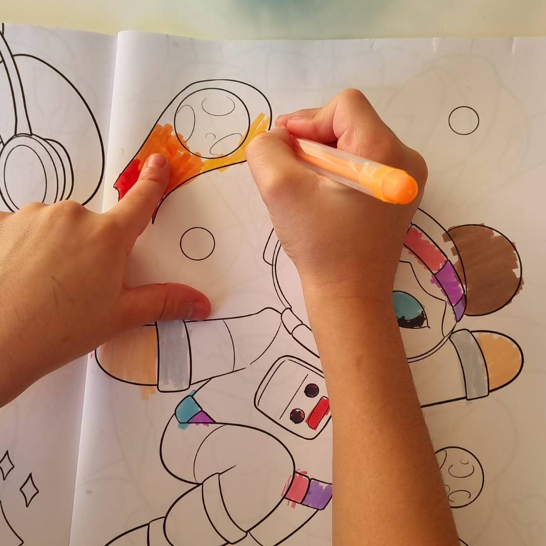 närbild på barnhänder som målar i watoto arts målarbok