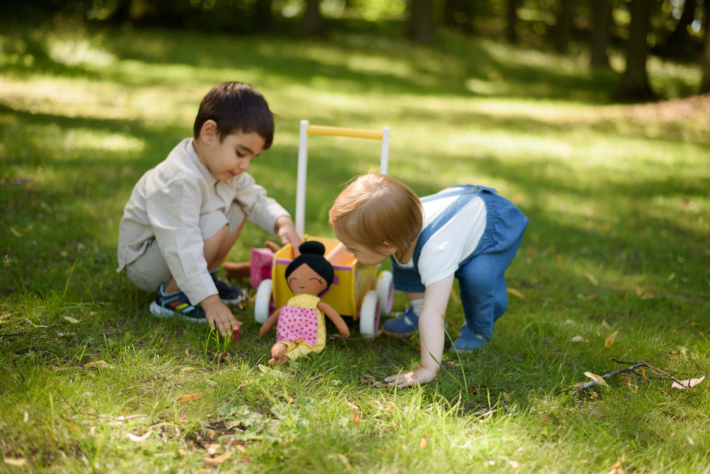två barn som leker utomhus med en mjuk docka