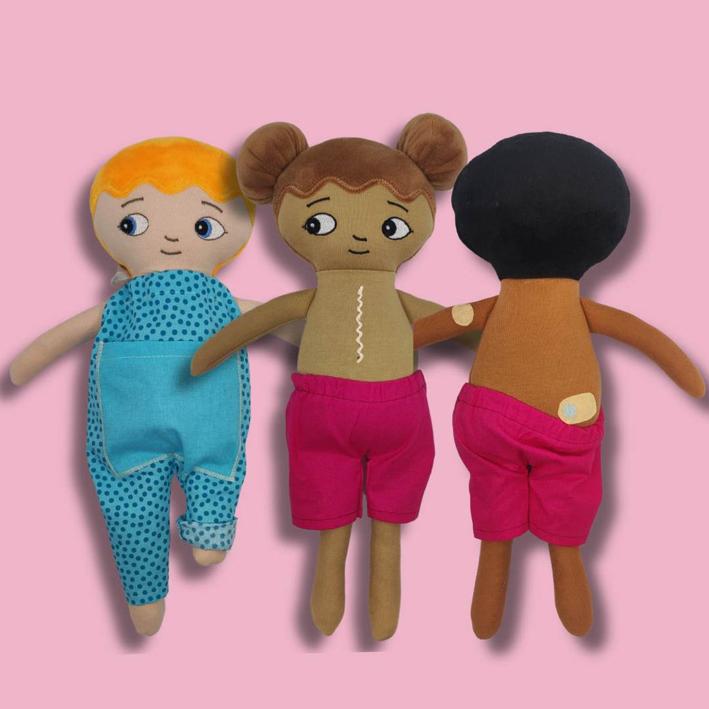 Tre dockor för lekterapi dockorna har diabetes, en docka har ett ärr över bröstet och en docka har hörapparat. 