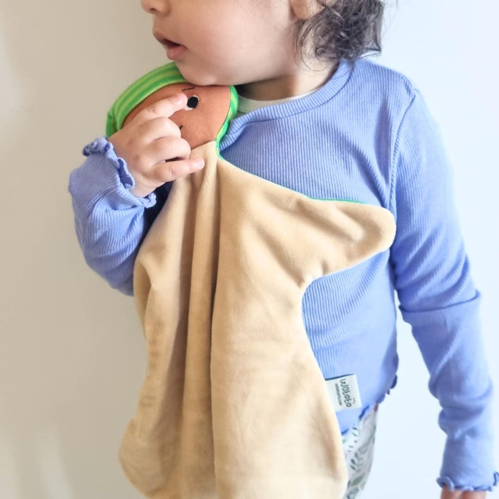 Ett barn som står upp och kramar sin snuttefilt
