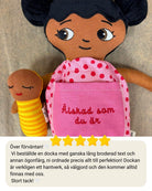 närbild på mjuk docka med personlig brodyr på klänning och en bebisdocka bredvid