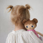 Ett barn som kramar sin watoto arts docka, barnet och dockan har samma frisyr