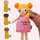 en hand håller mjuk docka med personlig brodyr och utbytbara bebisdockor i olika hudtoner