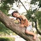 barn som klättrar i träd tillsammans med sin docka