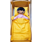 Pojkdocka från Watoto arts som bär pyjamas och liggen under det orangea täcket. 