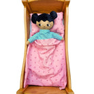 Watoto arts docka som bär pyjamas och liggen under täcket. 