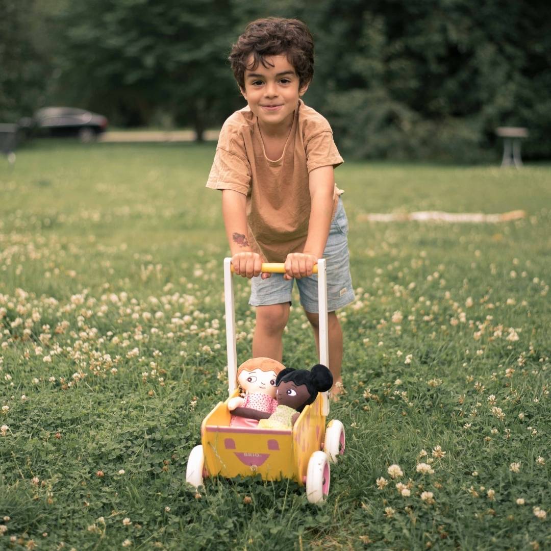 En pojke som kör sina watoto arts dockor i en dockvagn. 