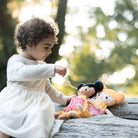 En flicka som leker med två watoto arts dockor utomhus