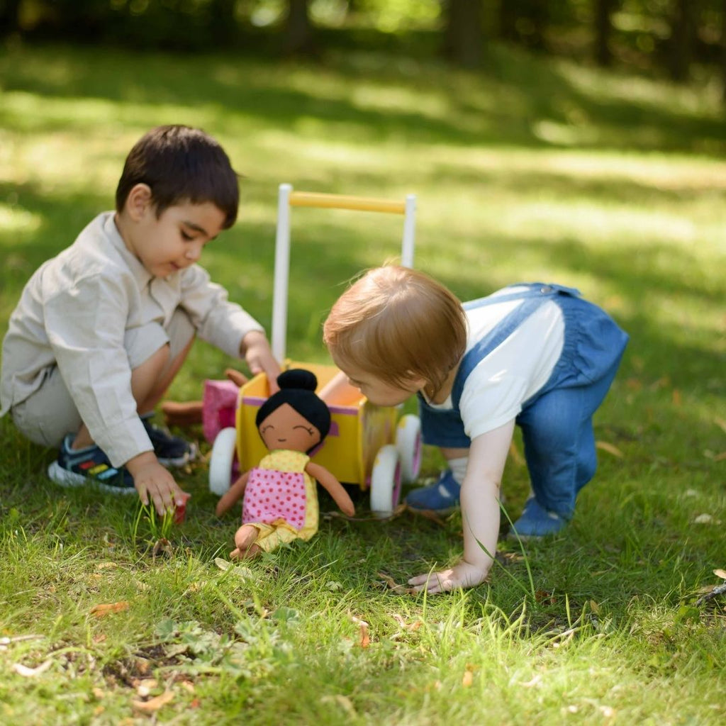 Två barn som leker utomhus med en mjuk docka