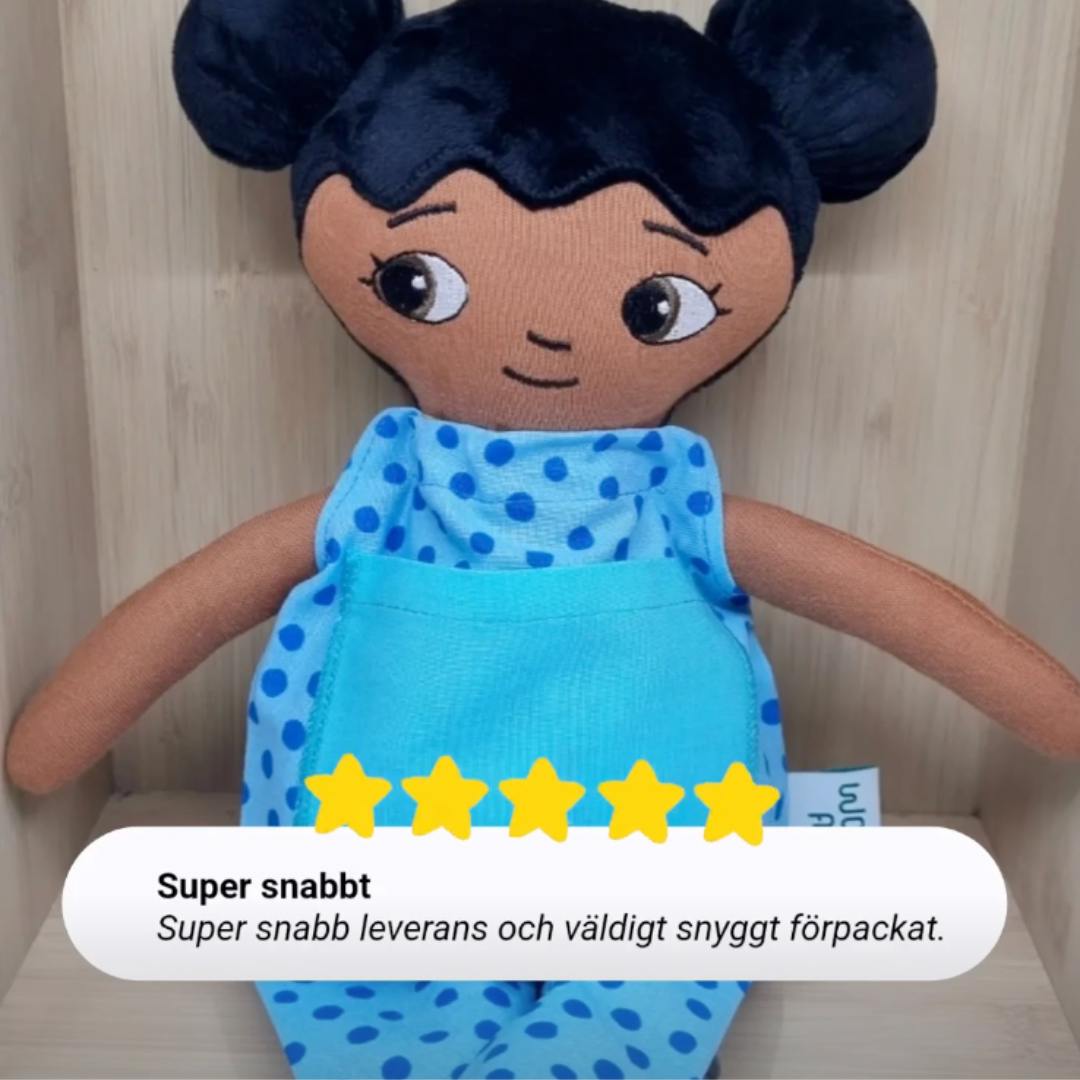 närbild på mjuk docka med personlig brodyr på kläderna samt en 5-stjärnig review från kund